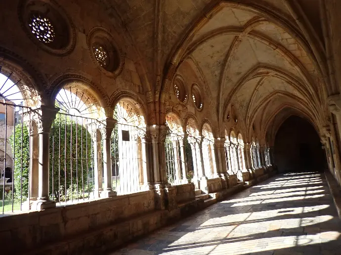 A long hallway with arched windows and a wrought iron fence